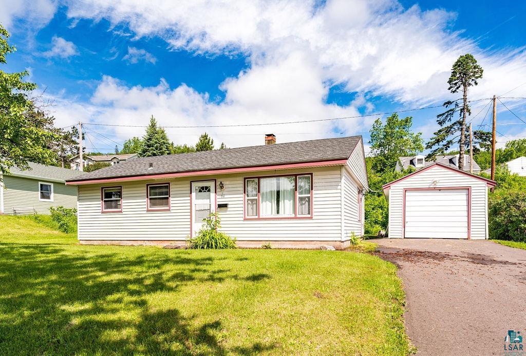 View of front of home with a front lawn, a garage, and an outdoor structure