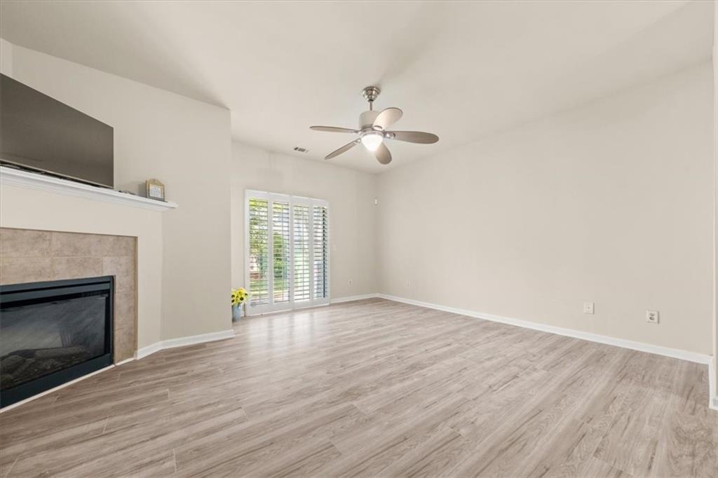 a view of an empty room with wooden floor fireplace and a window