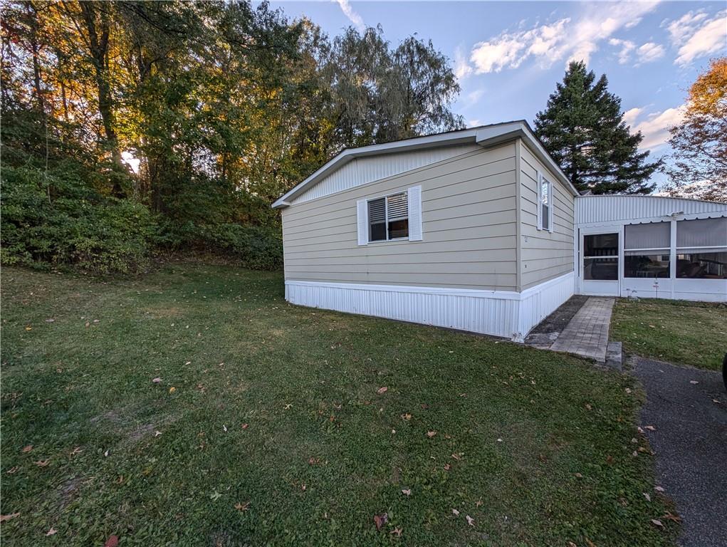 View of property exterior with a yard and a sunroom