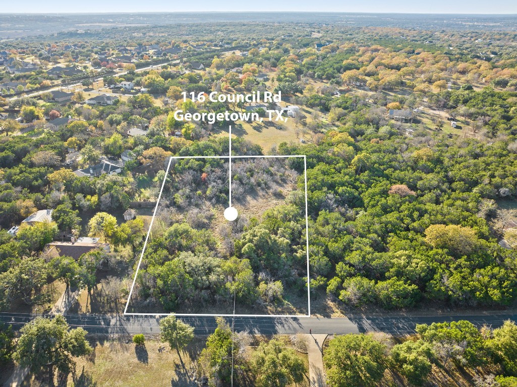 an aerial view of residential houses with outdoor space and trees