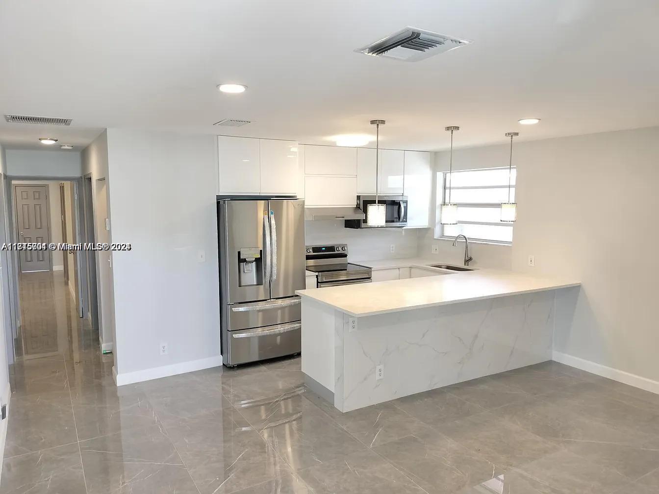 a large kitchen with a refrigerator a sink and a large window