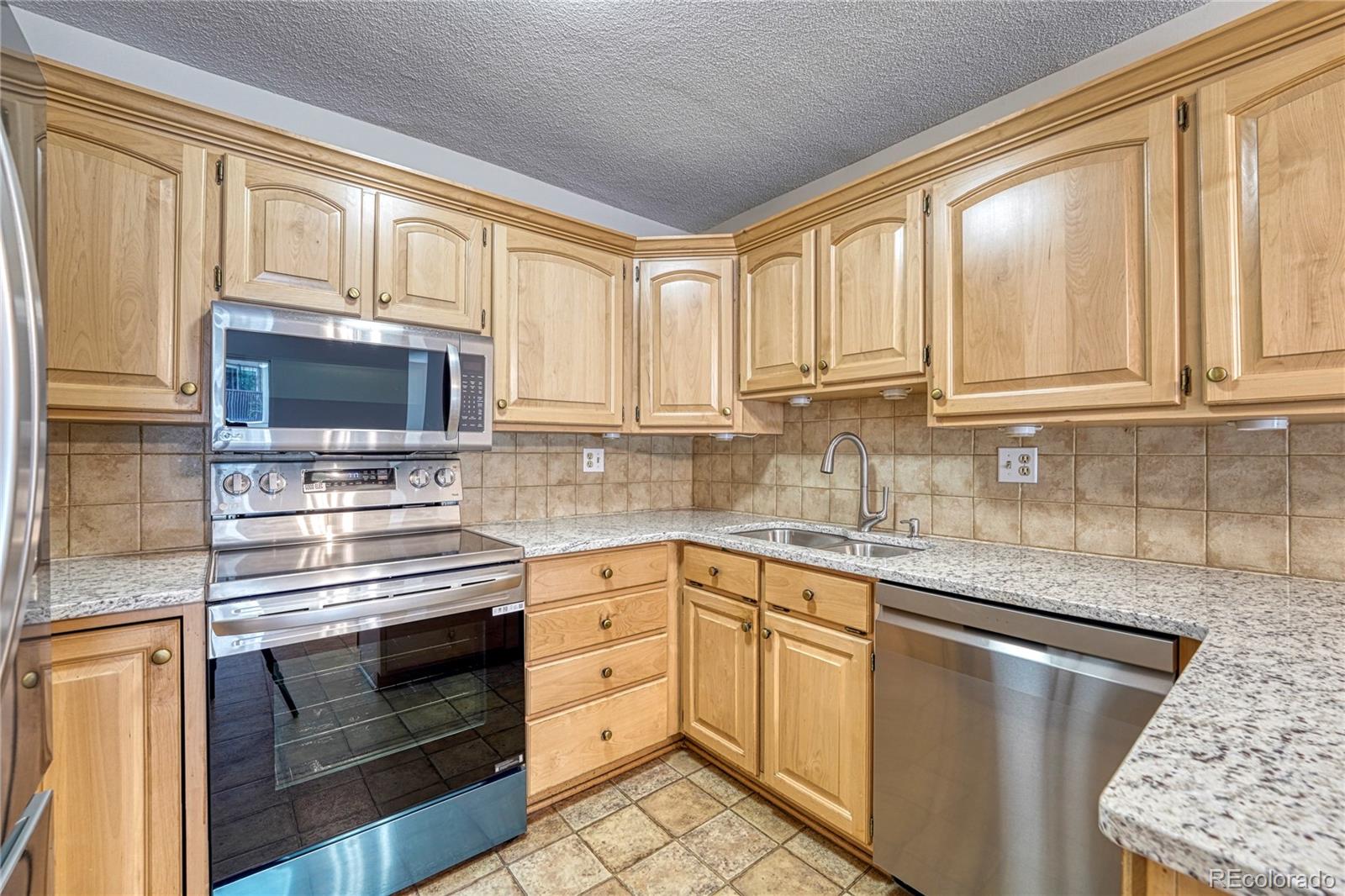 a kitchen with granite countertop white cabinets stainless steel appliances and a window