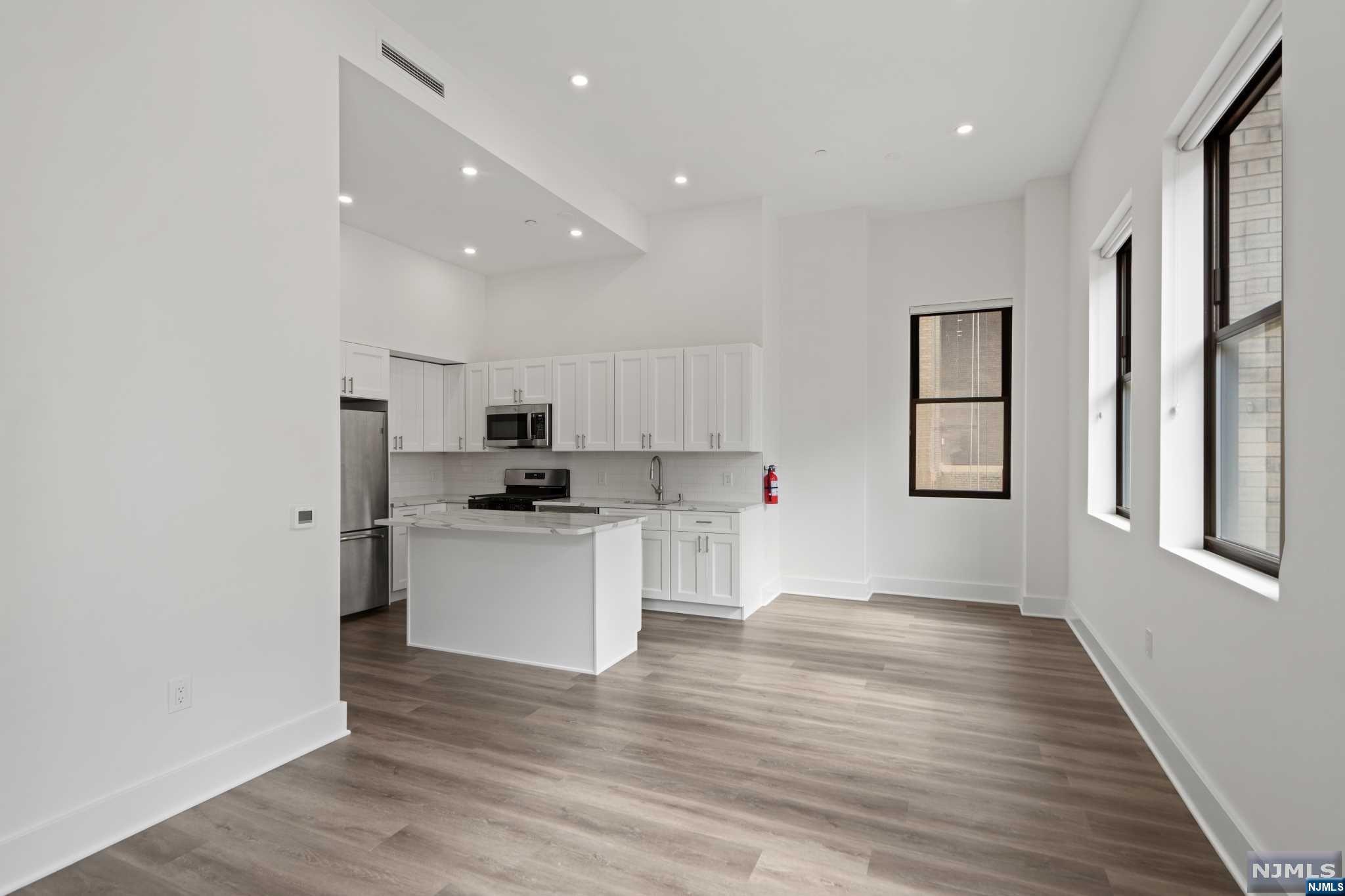 a kitchen with stainless steel appliances granite countertop a refrigerator sink and white cabinets