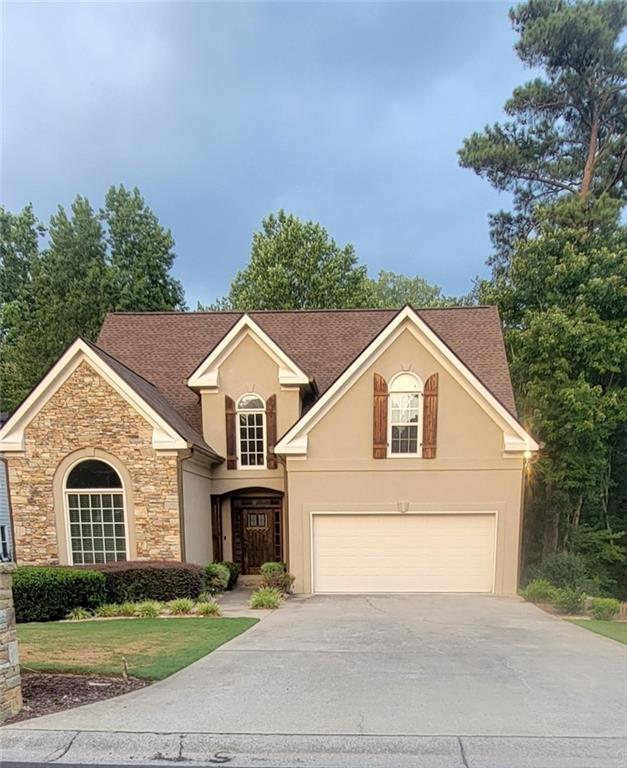 a front view of a house with a garden and trees