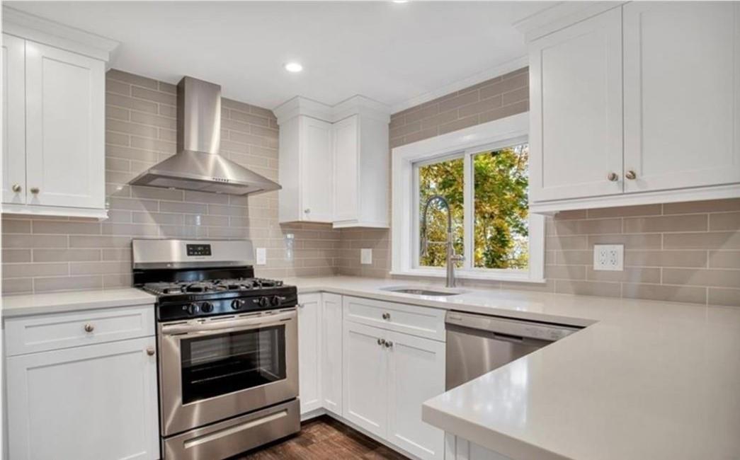 a kitchen with stainless steel appliances white cabinets and a stove top oven