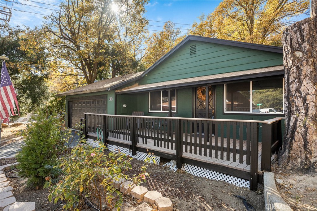 a view of house with a deck and a yard