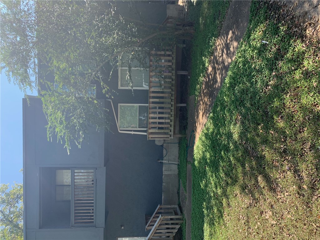 Back of house with a yard and a balcony