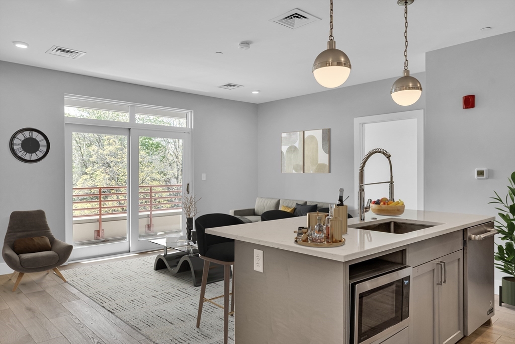 a kitchen with a sink appliances and living room view