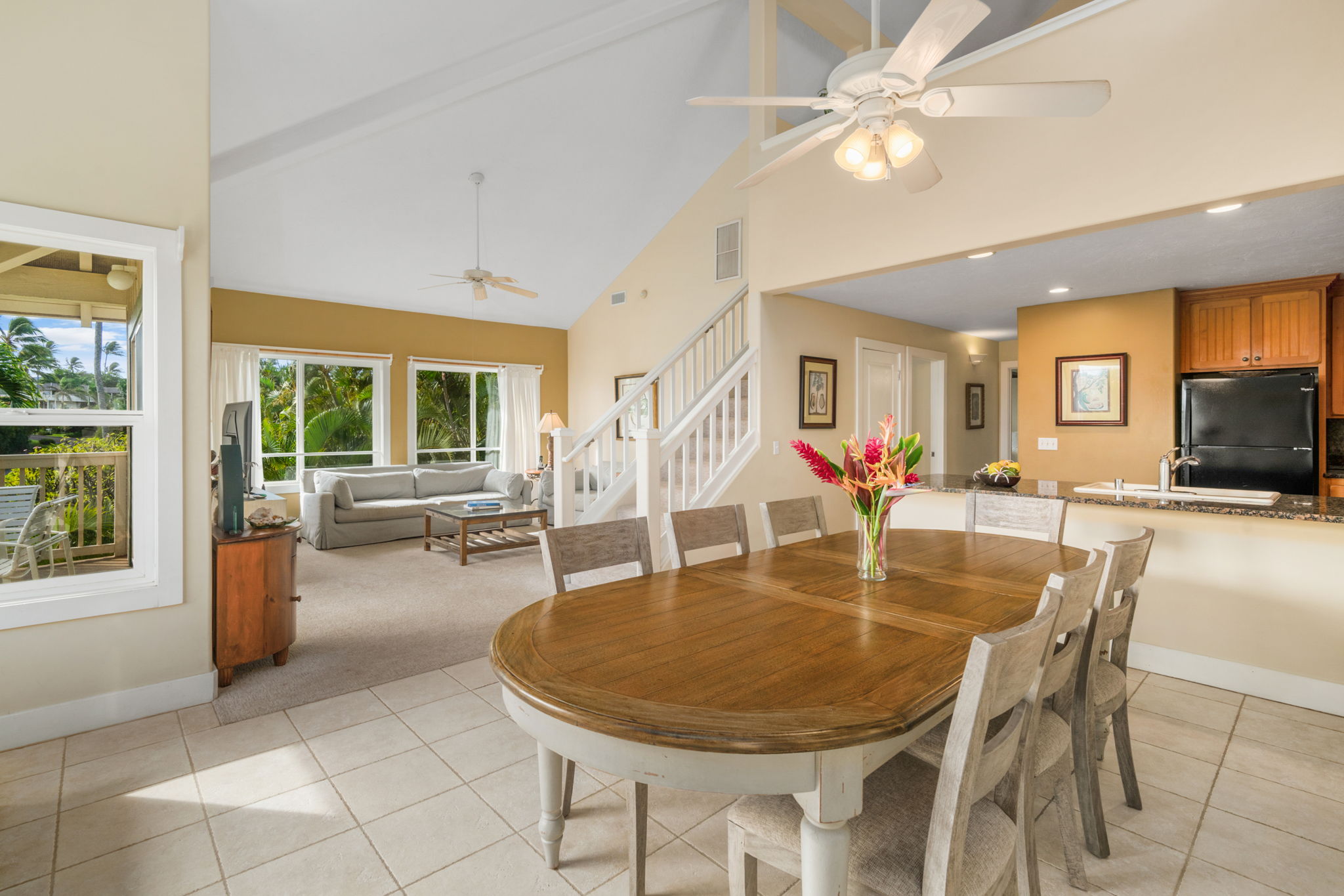 a dining room with wooden floor a chandelier fan a wooden table and chairs