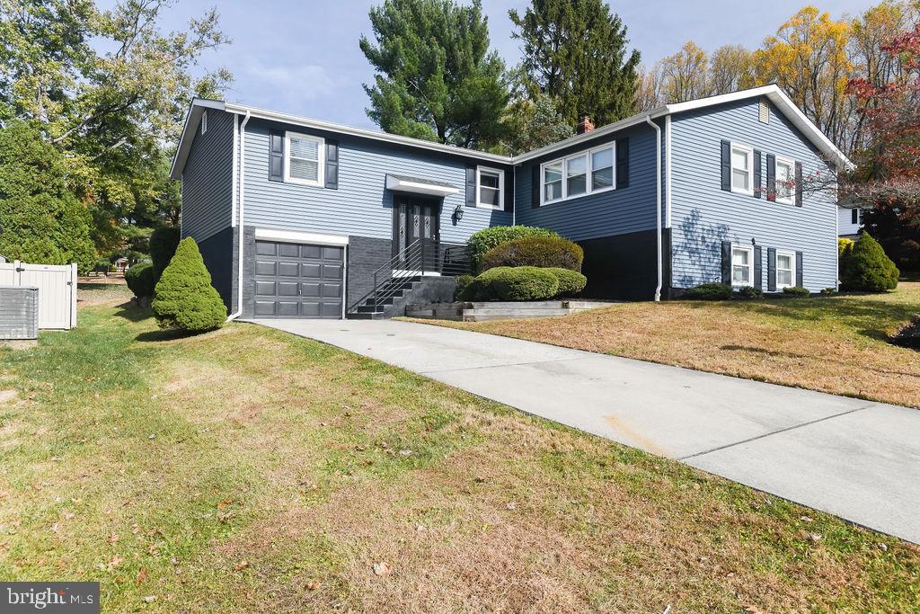 a view of a house with a yard and large tree