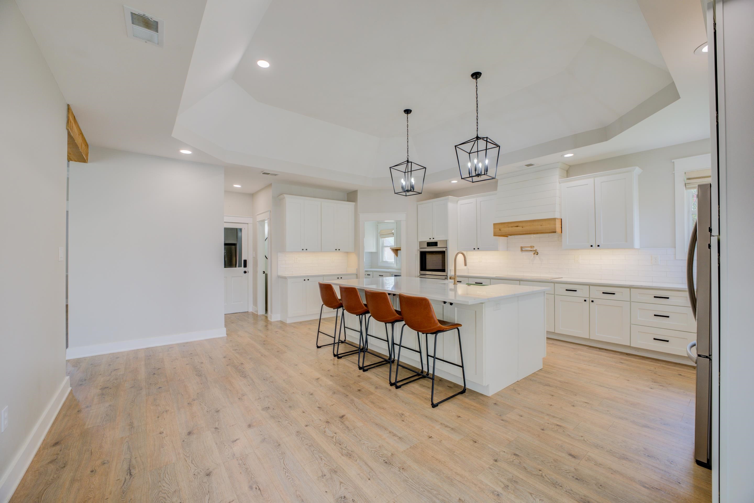 a large white kitchen with lots of counter space wooden floor and appliances