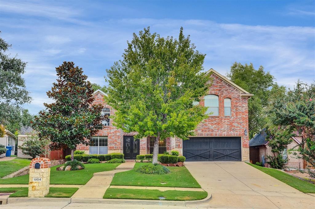 View of property hidden behind natural elements with a front yard and a garage