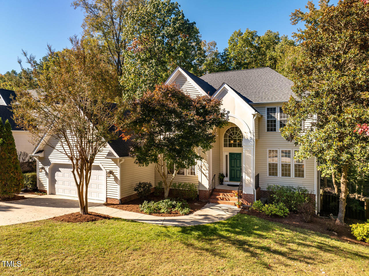 a front view of a house with garden and trees