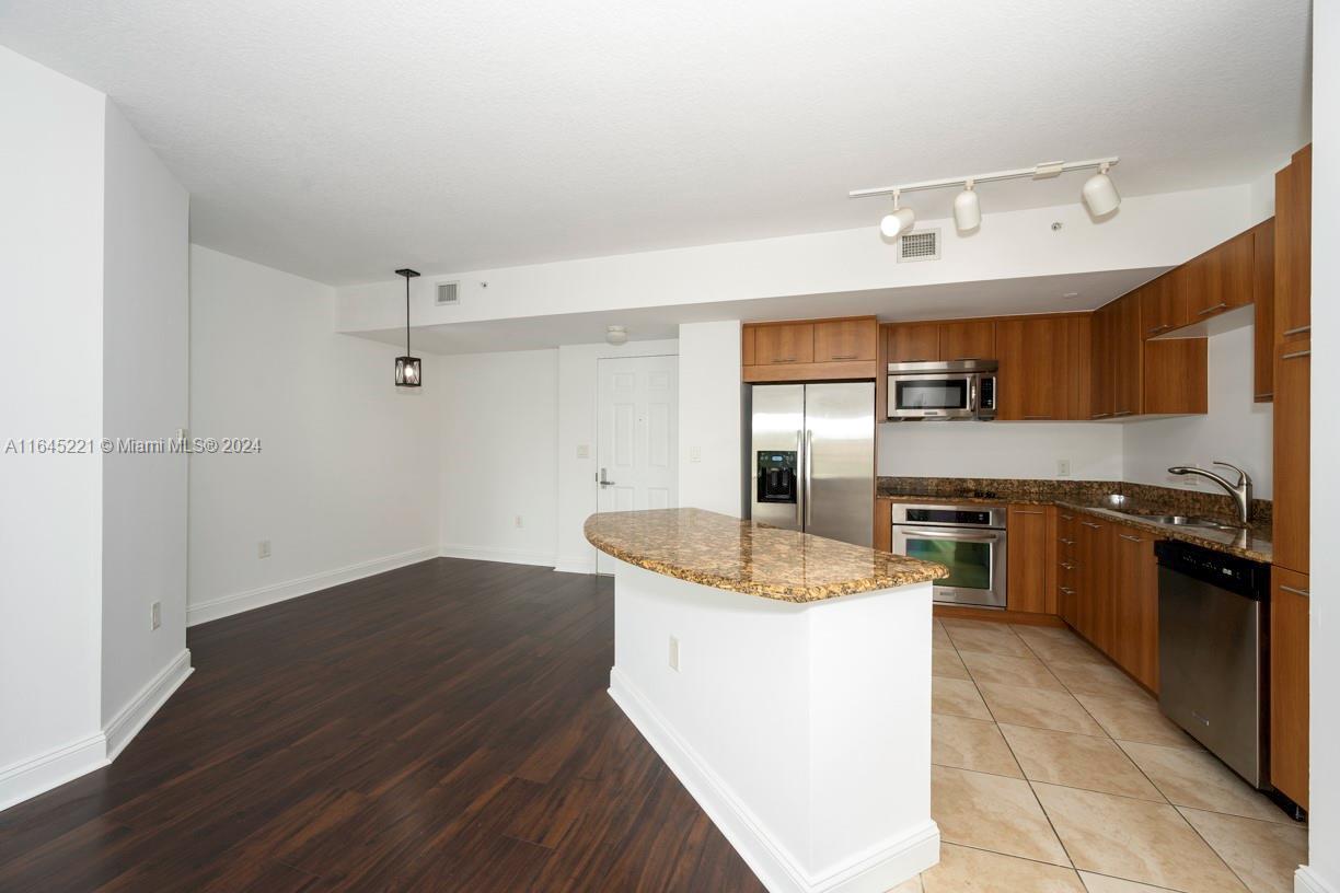 a kitchen with stainless steel appliances granite countertop a sink and a refrigerator