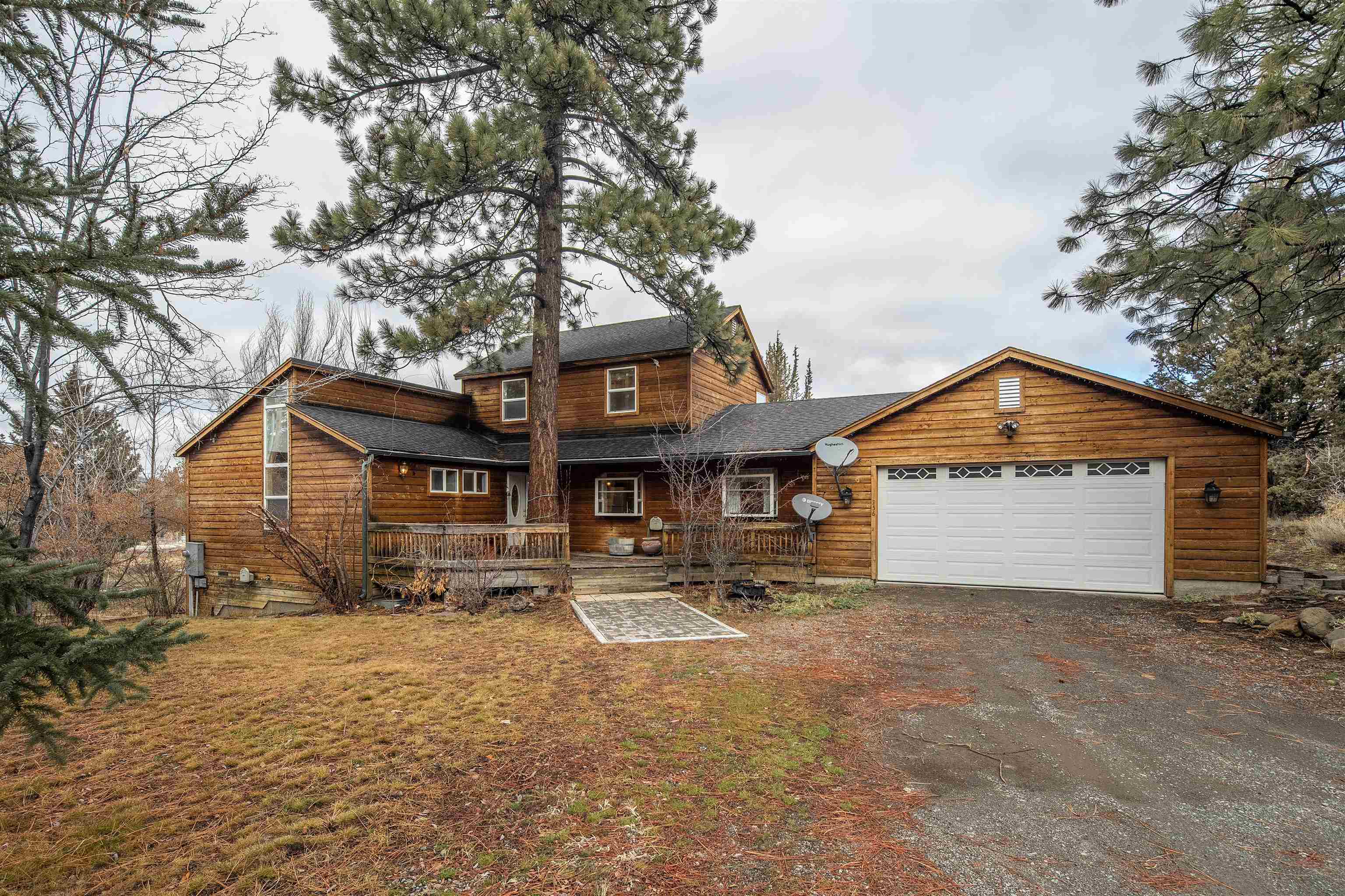 a front view of a house with a yard and large tree