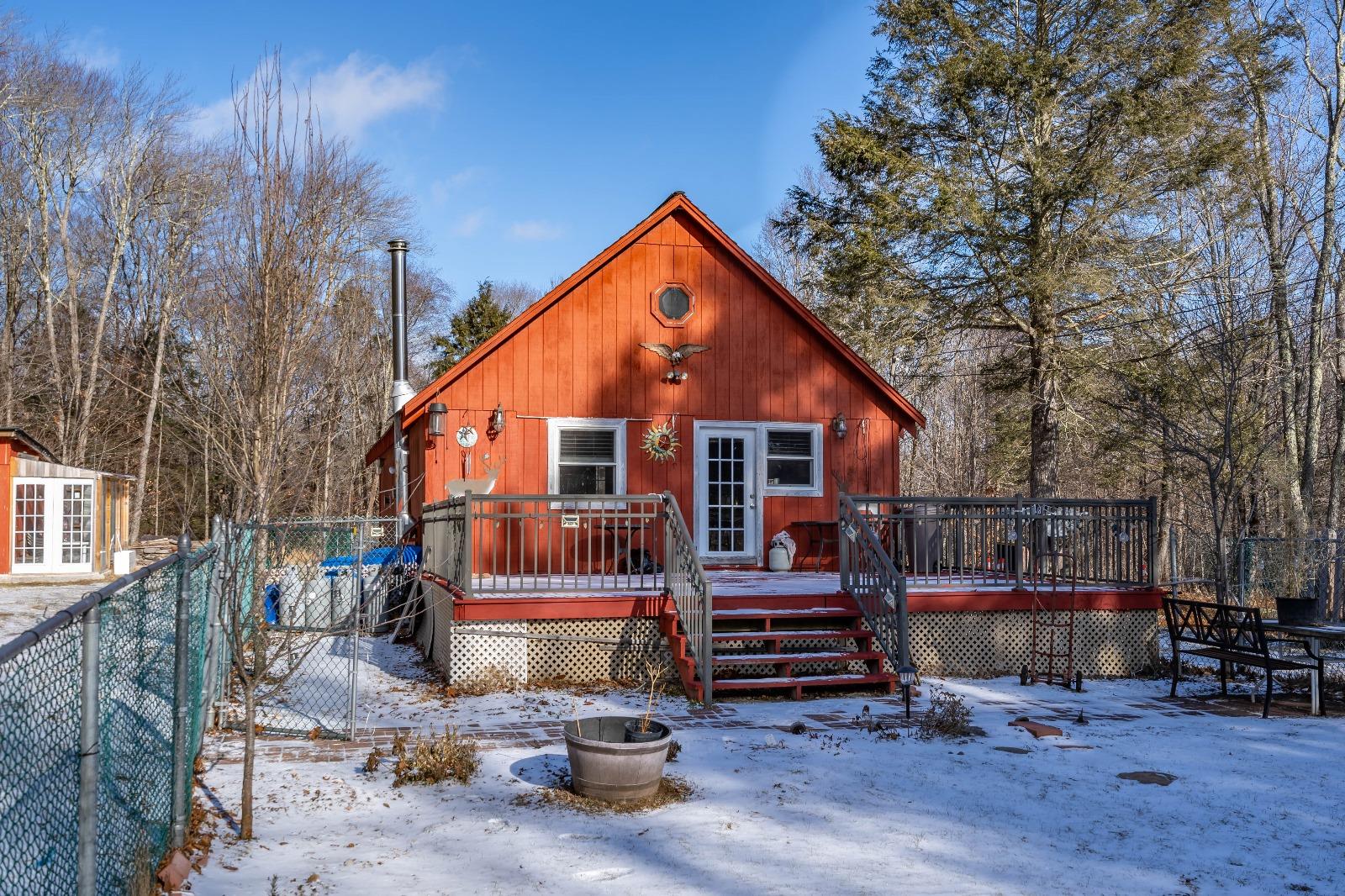 Snow covered back of property featuring a deck