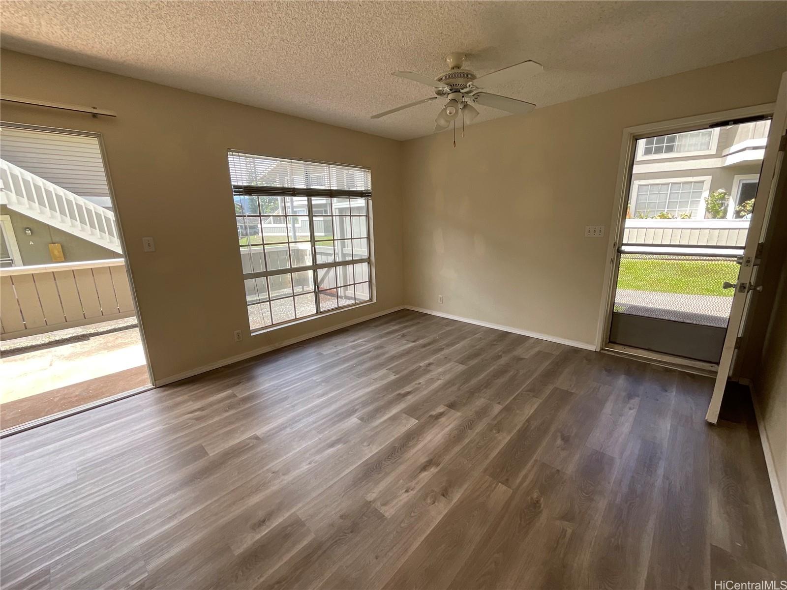 an empty room with wooden floor fan and windows