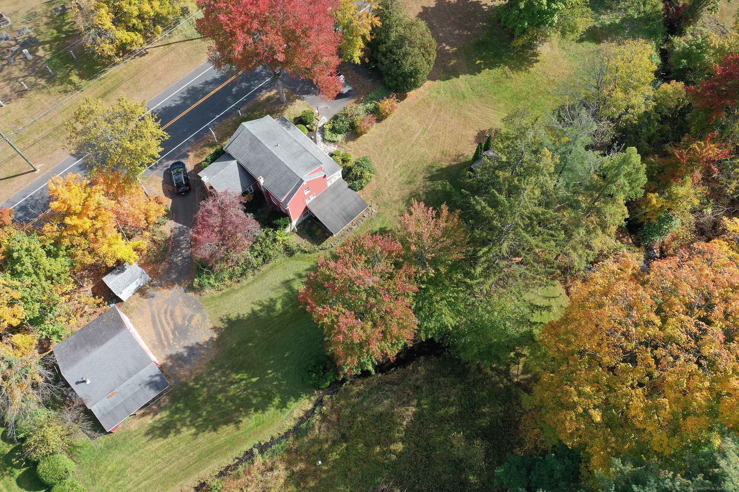 an aerial view of residential house with outdoor space and trees all around