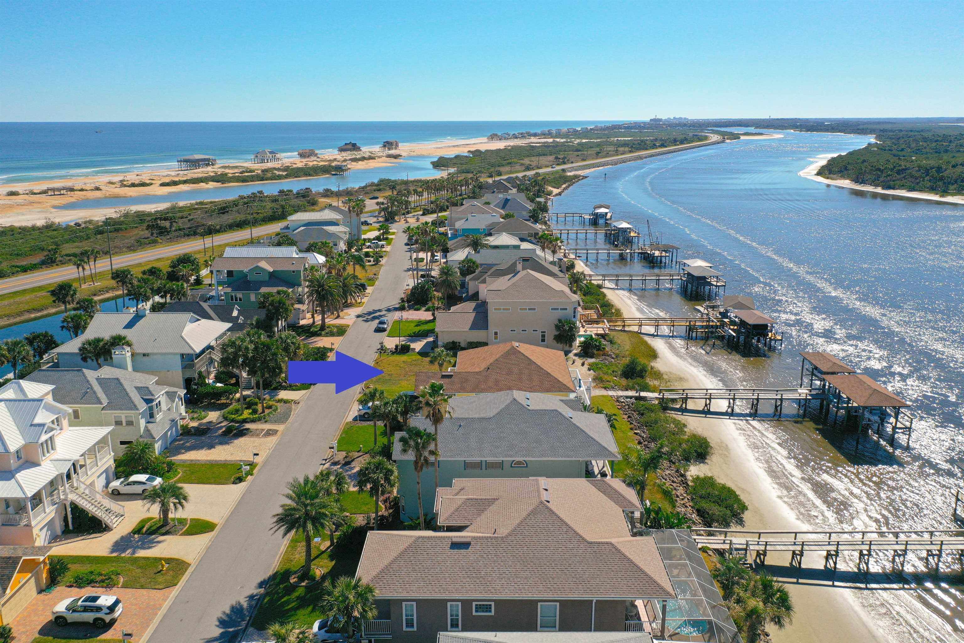 an aerial view of ocean and residential houses with outdoor space