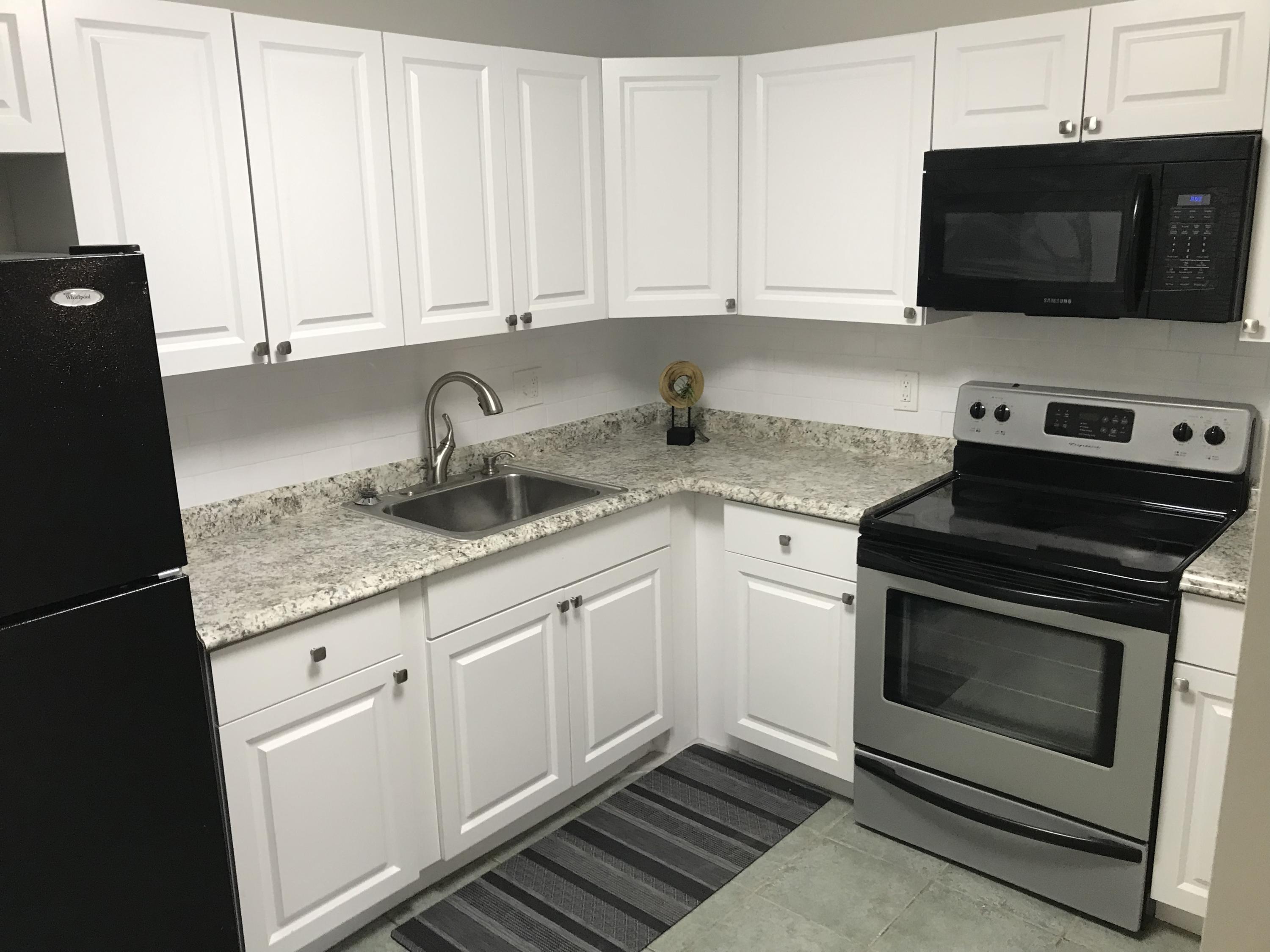 a kitchen with granite countertop white cabinets and white appliances