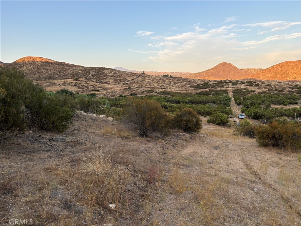 a view of a dry field with mountains in the background