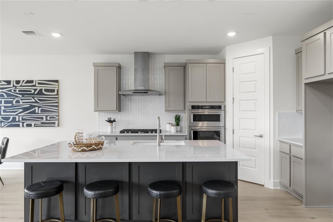 a kitchen with stainless steel appliances a dining table chairs and wooden floor