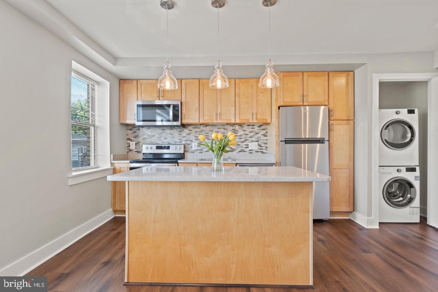 a kitchen with a refrigerator a stove a sink and a window with wooden floor