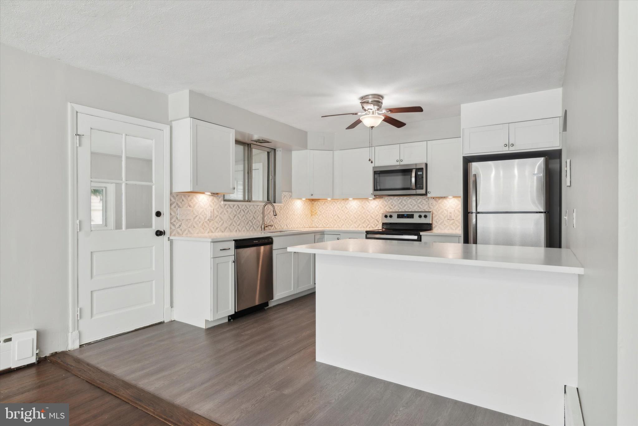 a kitchen with granite countertop a refrigerator stove top oven and sink