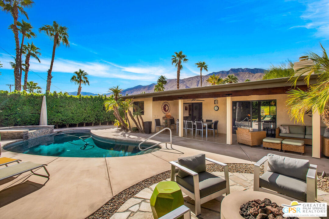 a view of a patio with couches table and chairs potted plants and palm tree