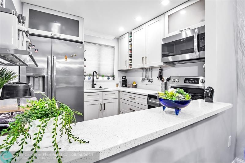 a kitchen with stainless steel appliances kitchen island granite countertop a sink a stove and a refrigerator