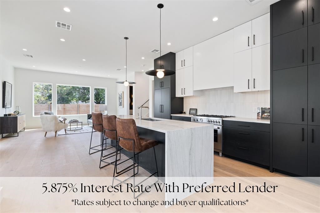 a living room with stainless steel appliances kitchen island granite countertop a table chairs and a view of kitchen