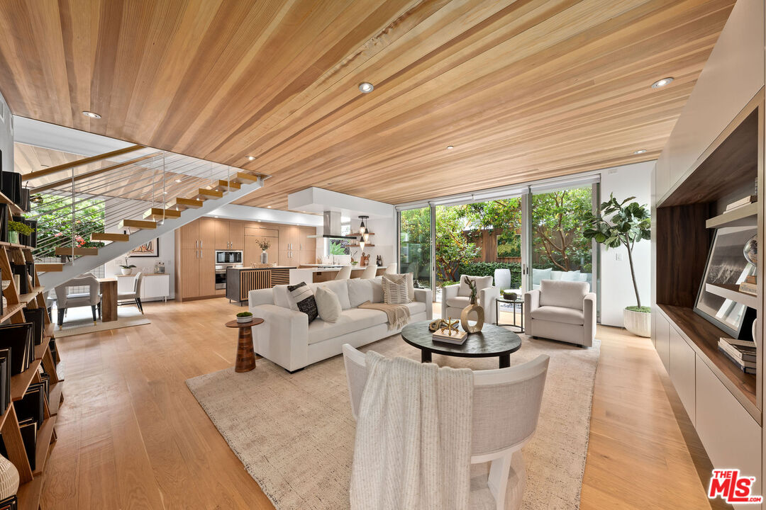 a living room with furniture a flat screen tv and floor to ceiling window