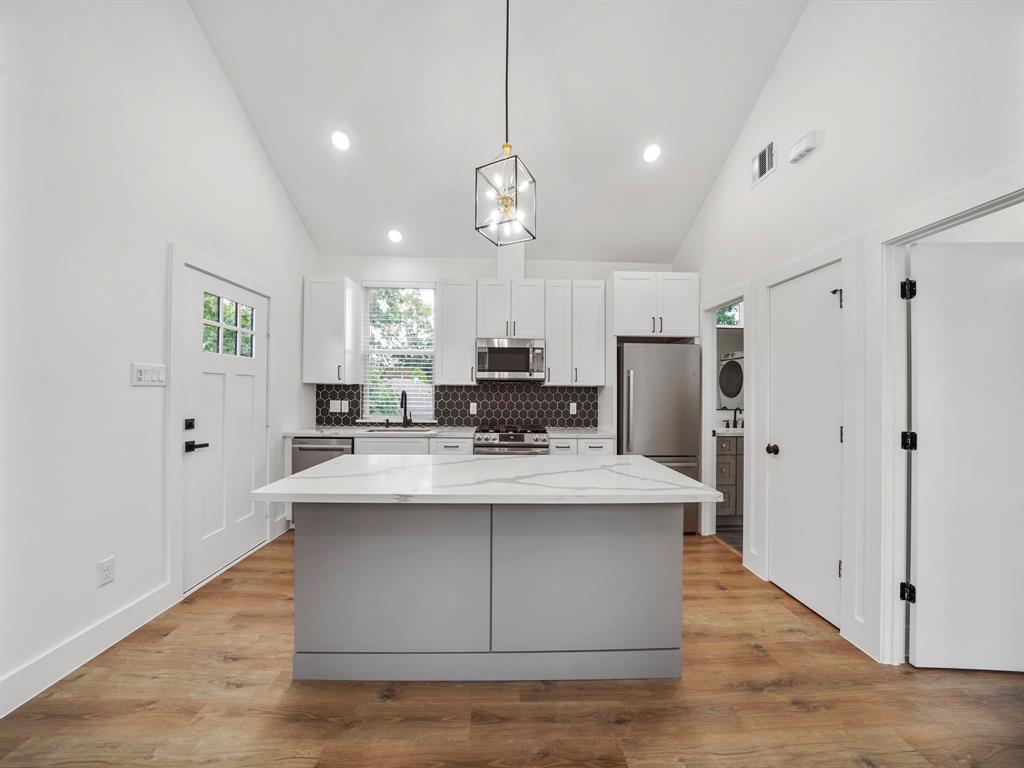 a view of a kitchen with kitchen island a island wooden floor stainless steel appliances and cabinets