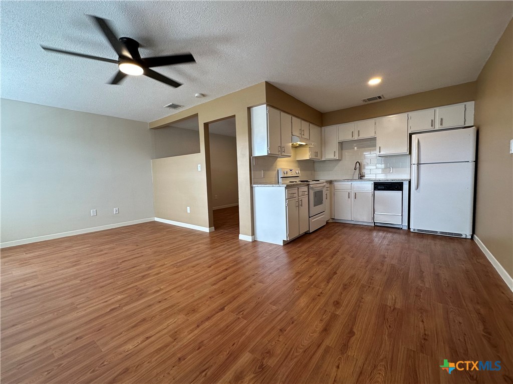 a view of a kitchen with a sink and dishwasher a refrigerator with wooden floor