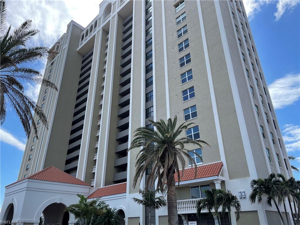 a front view of multi story residential apartment building with yard and parking space