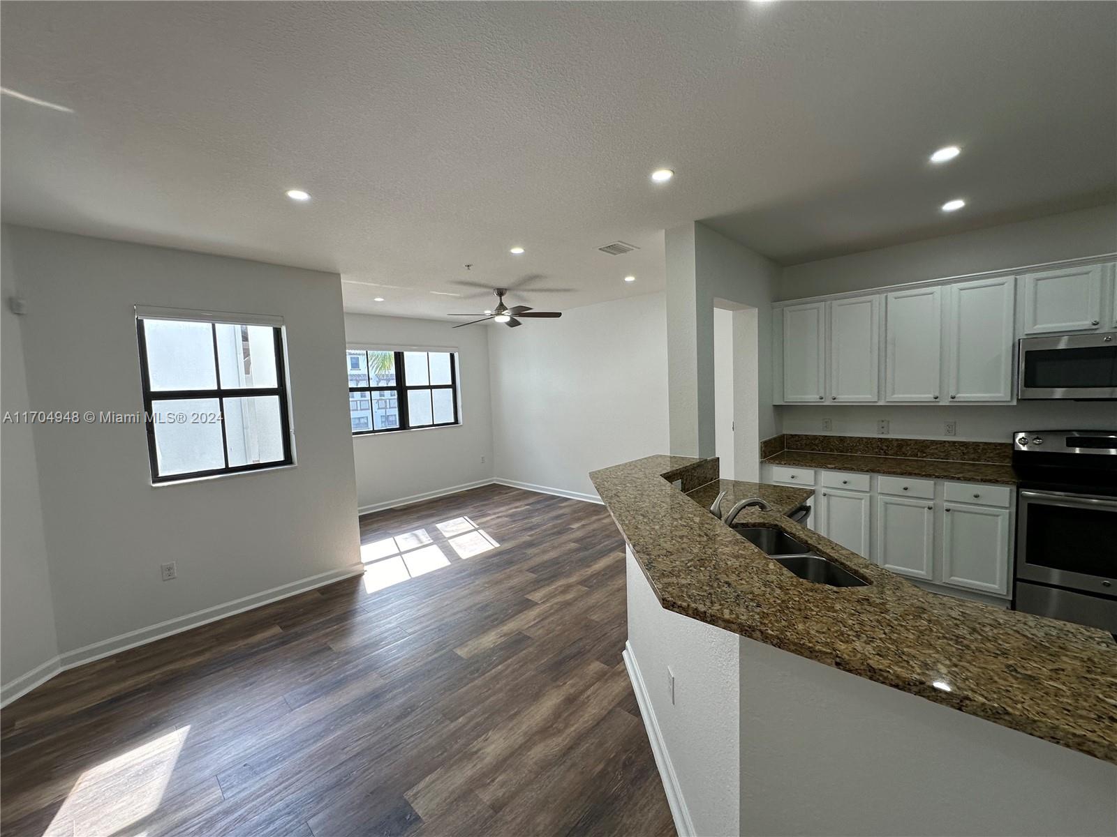 a kitchen with granite countertop a stove a sink and a refrigerator