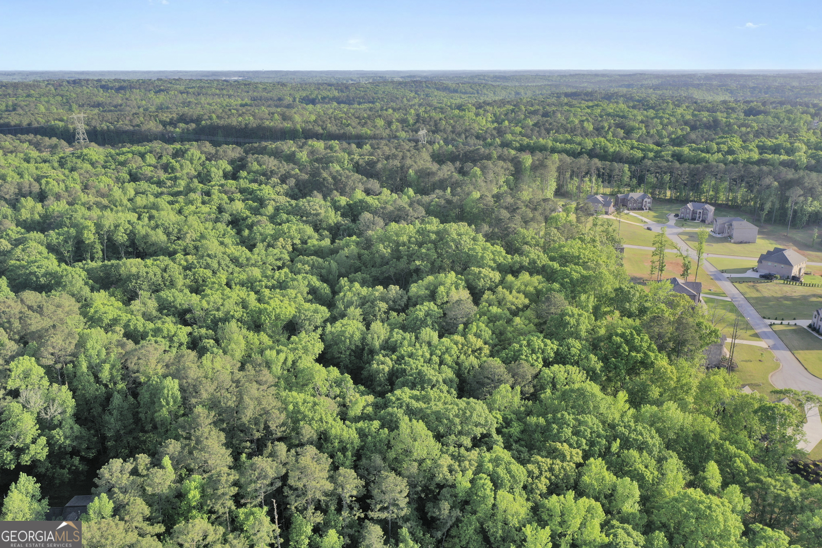 an aerial view of residential houses with outdoor space and trees