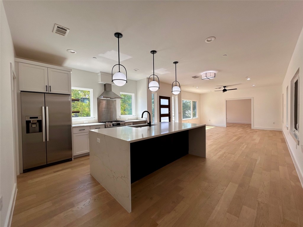 a large kitchen with stainless steel appliances kitchen island granite countertop a refrigerator a oven a kitchen island a sink and a wooden floors