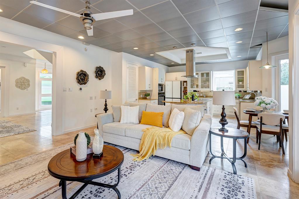 a living room with furniture kitchen view and a chandelier