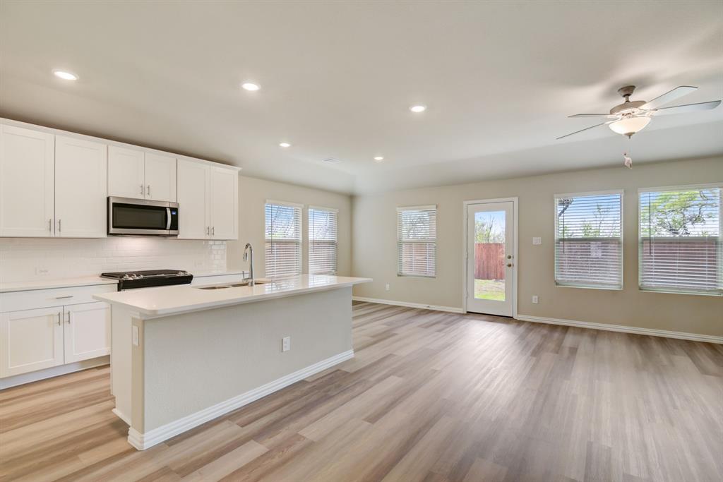 a kitchen with stainless steel appliances granite countertop a stove top oven a sink dishwasher a refrigerator and white cabinets with wooden floor