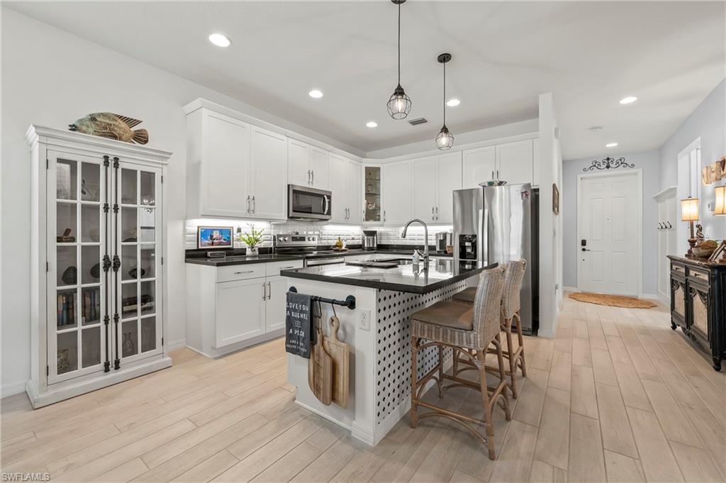 a kitchen with stainless steel appliances kitchen island granite countertop a stove top oven a refrigerator a sink and a dining table with wooden floor
