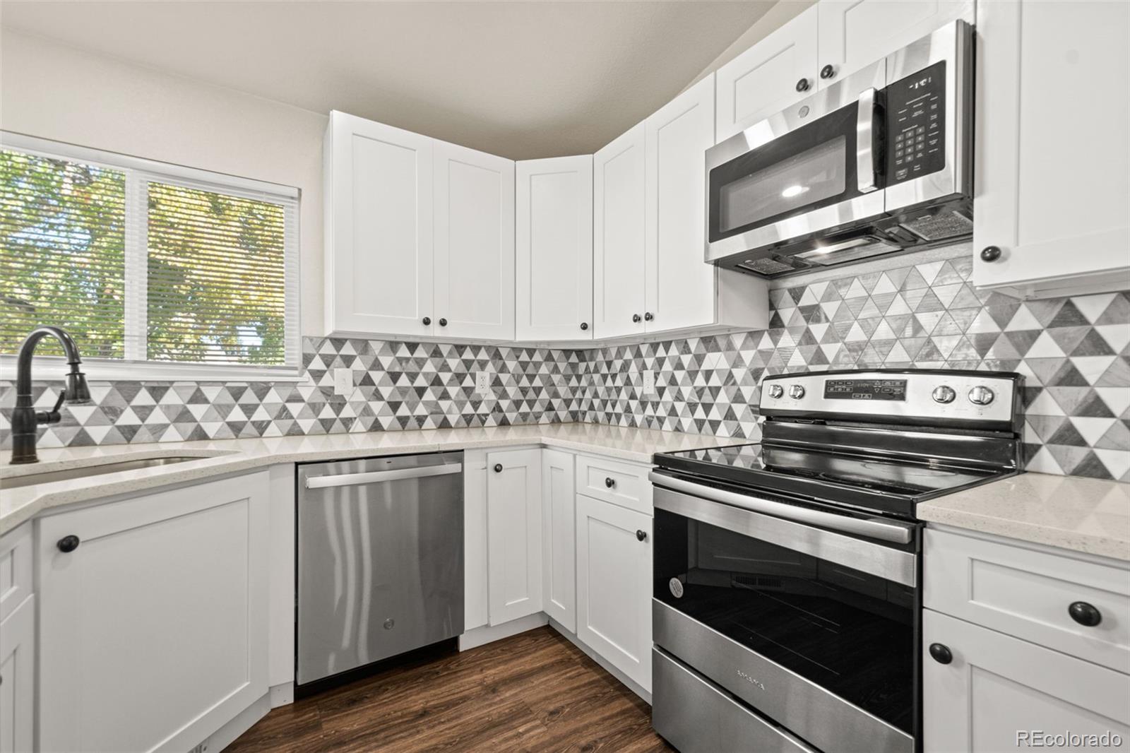 a kitchen with cabinets appliances a sink and a window