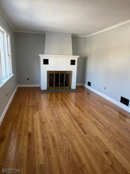 an empty room with wooden floor fireplace and windows