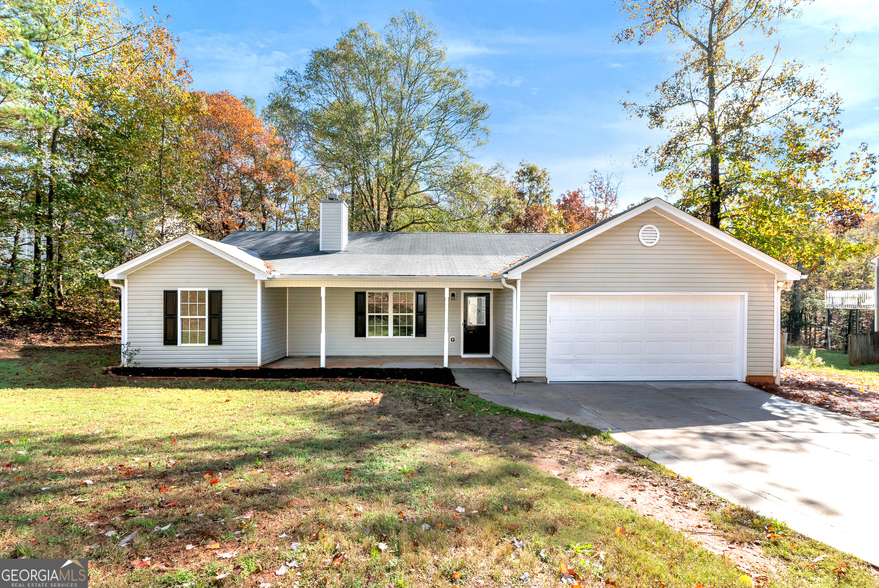 a front view of house with yard and trees in the background