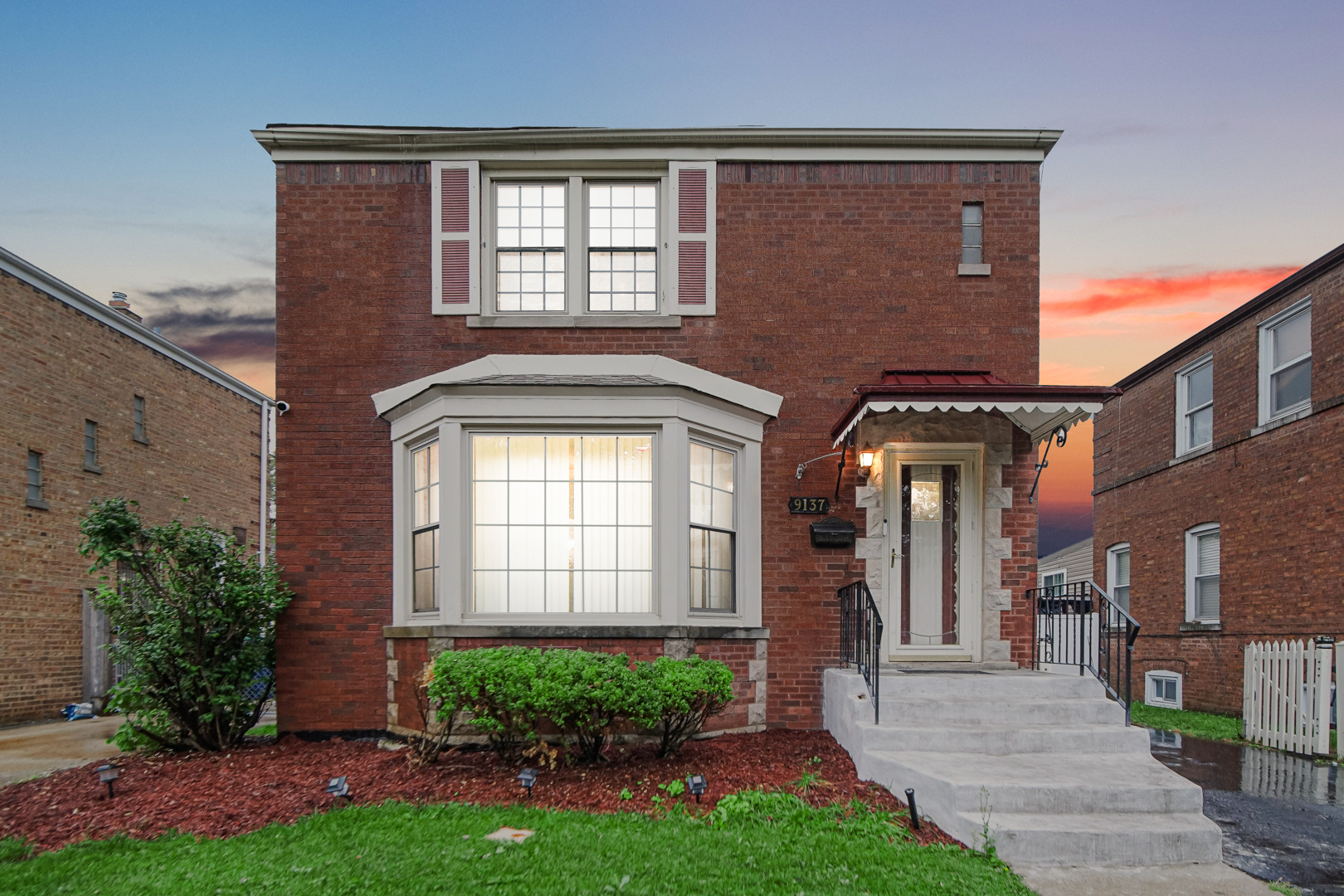 front view of a brick house with a yard