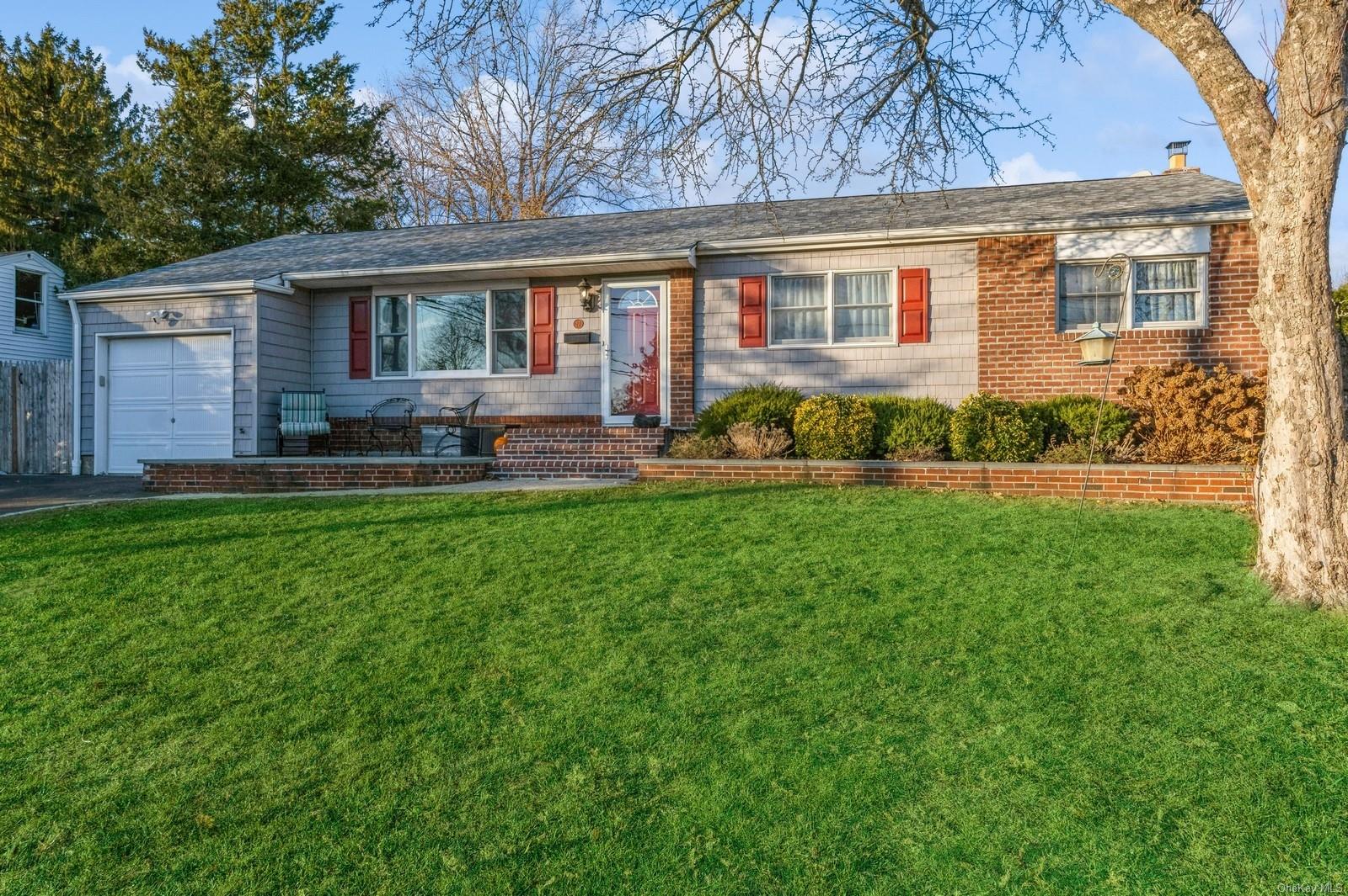 Ranch-style home featuring a garage and a front lawn