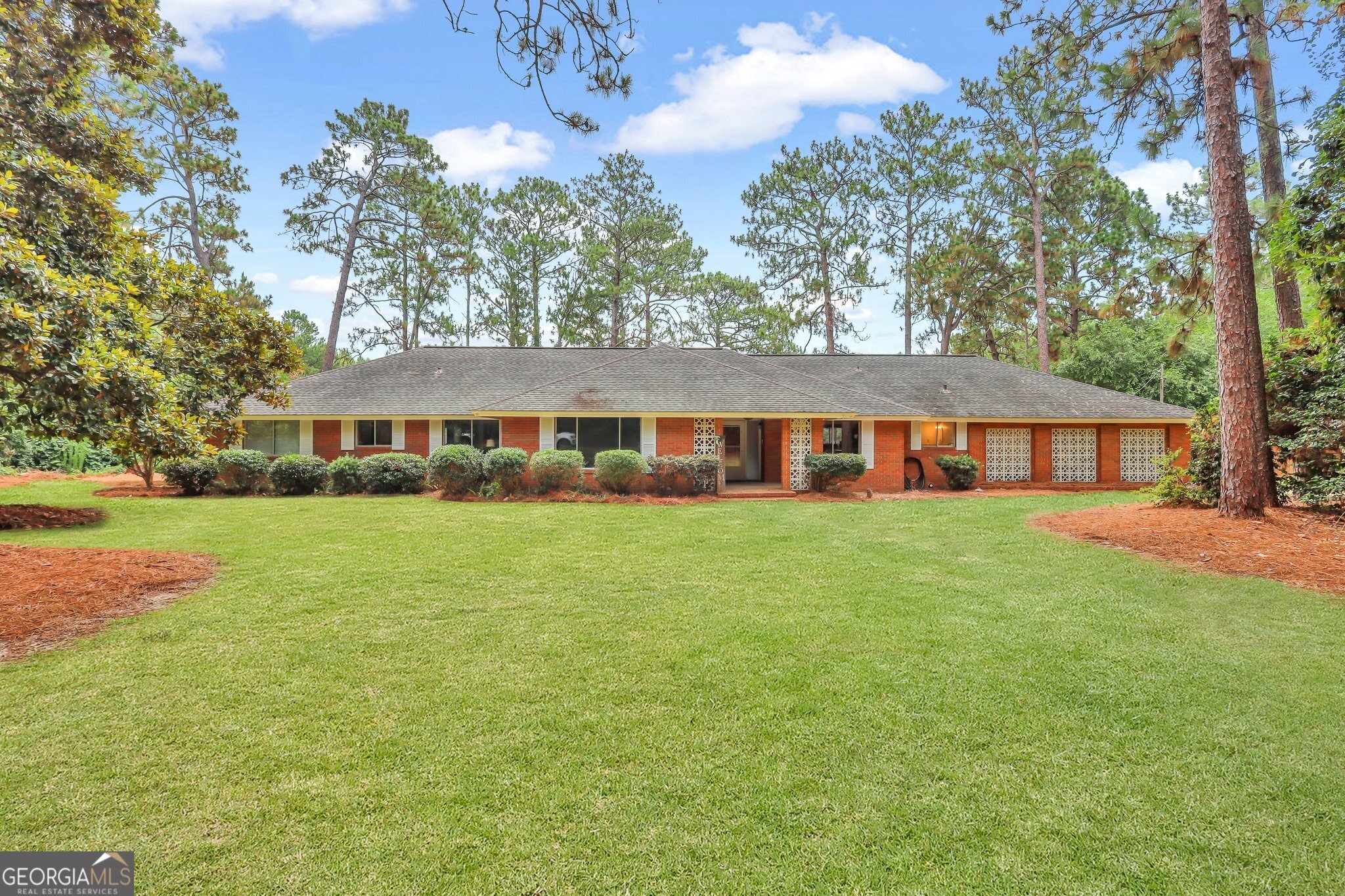 a front view of house with yard and trees in the background