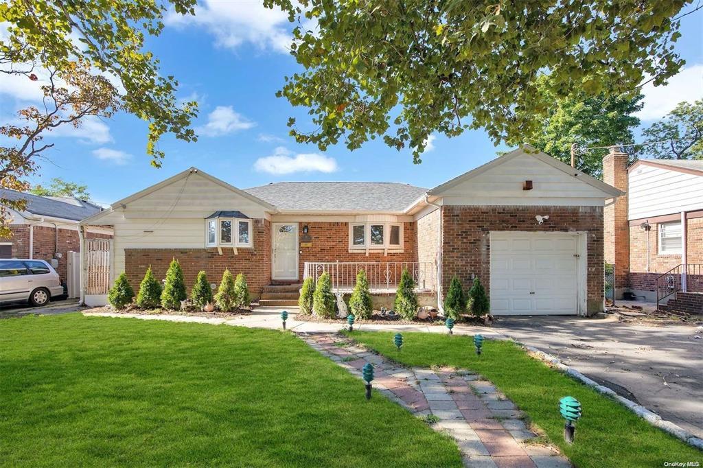 Single story home with a garage and a front lawn