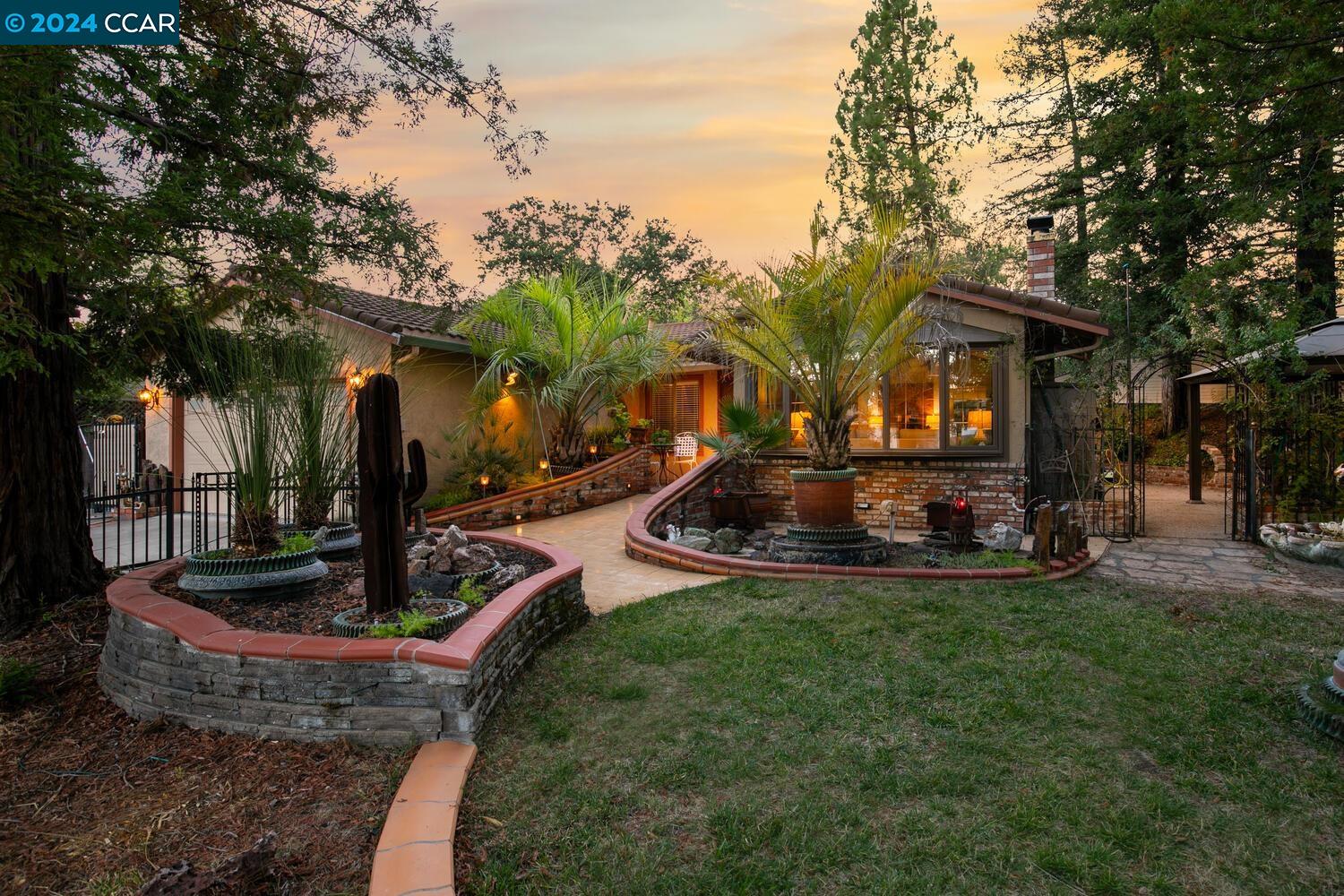 a front view of a house with garden and trees