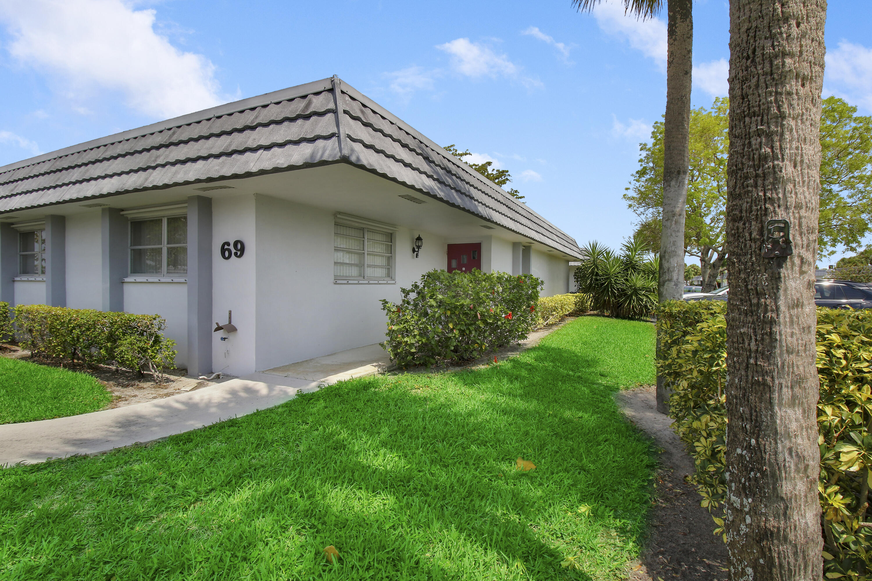 a view of a house with a small yard and a palm tree